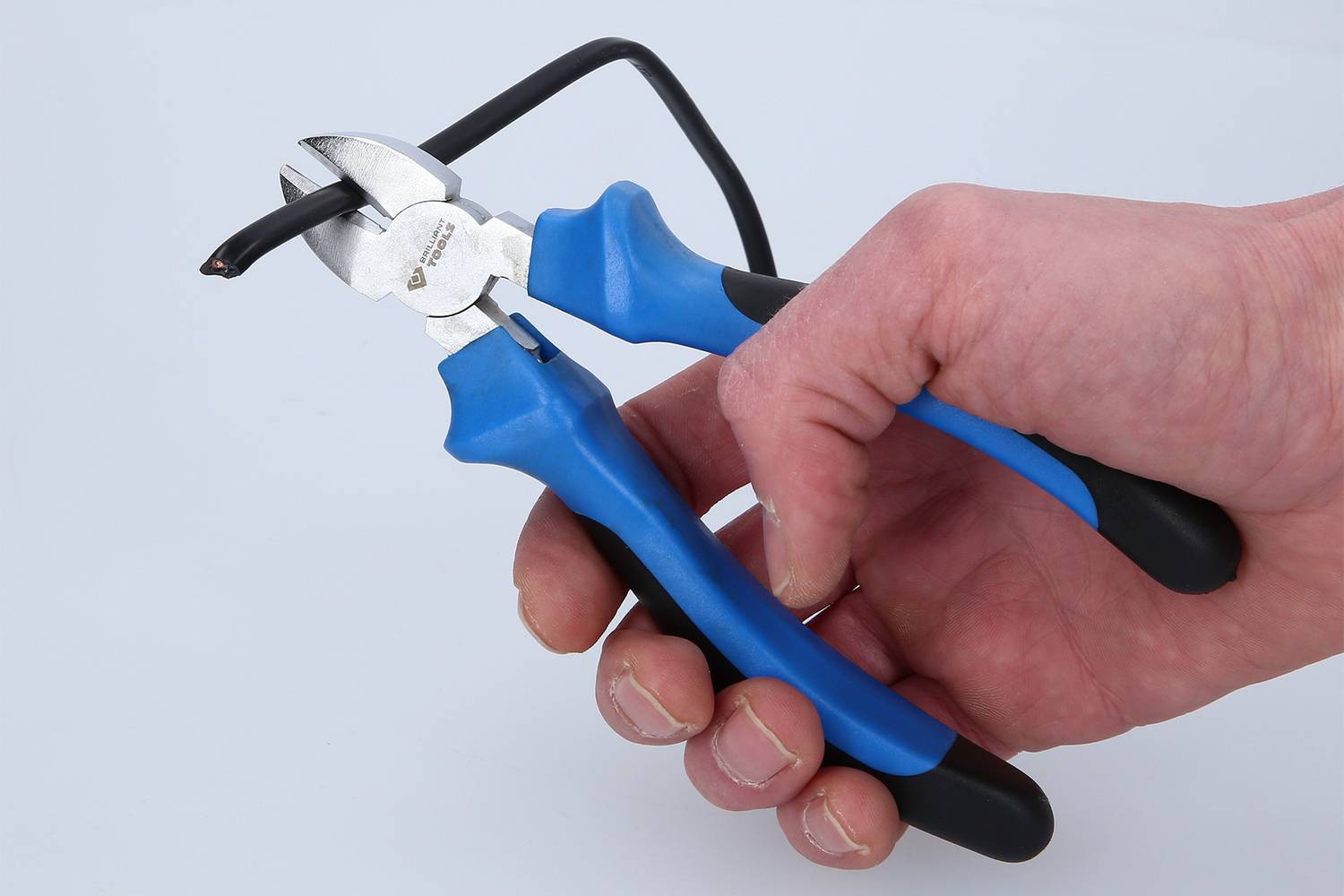 Eine Hand hält einen blauen Seitenschneider, der ein schwarzes Kabel durchtrennt.