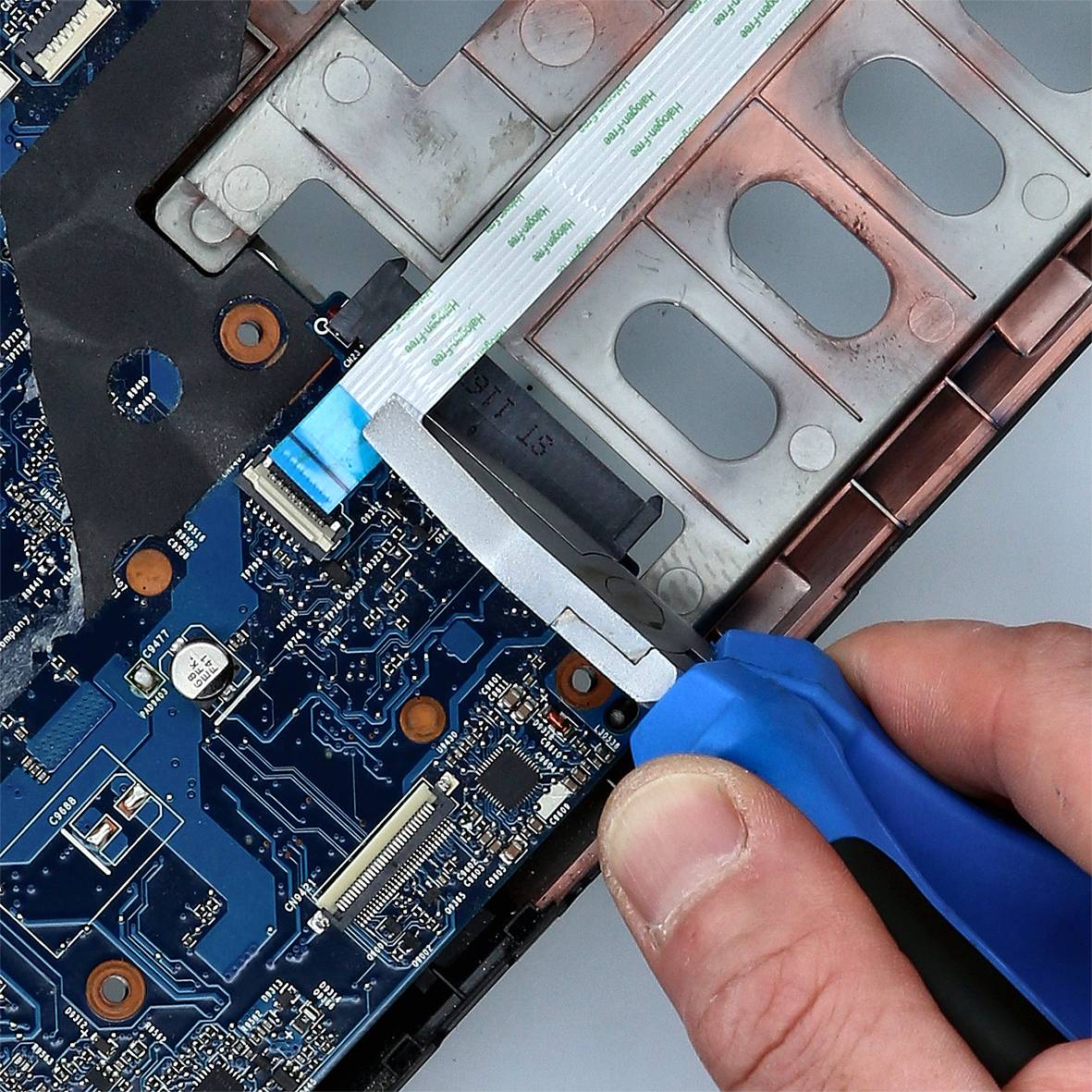 Nahaufnahme einer Person, die mit einer Zange vorsichtig ein flaches Kabel von einer Computerplatine entfernt.