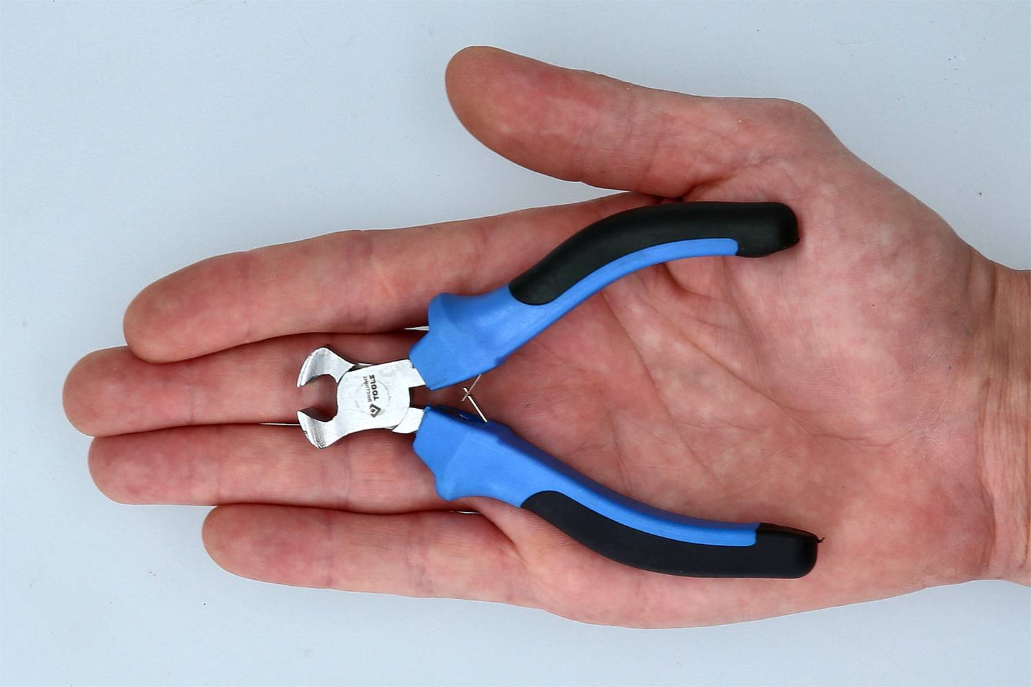 Eine Hand hält einen kleinen, blauen Drahtschneider, der für Bastelarbeiten geeignet ist.