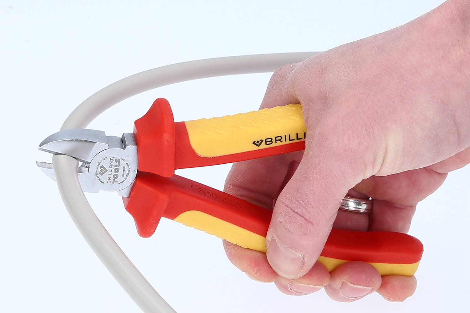 Eine Hand hält einen roten Seitenschneider der Marke BRILLIANT TOOLS und schneidet ein graues Kabel.