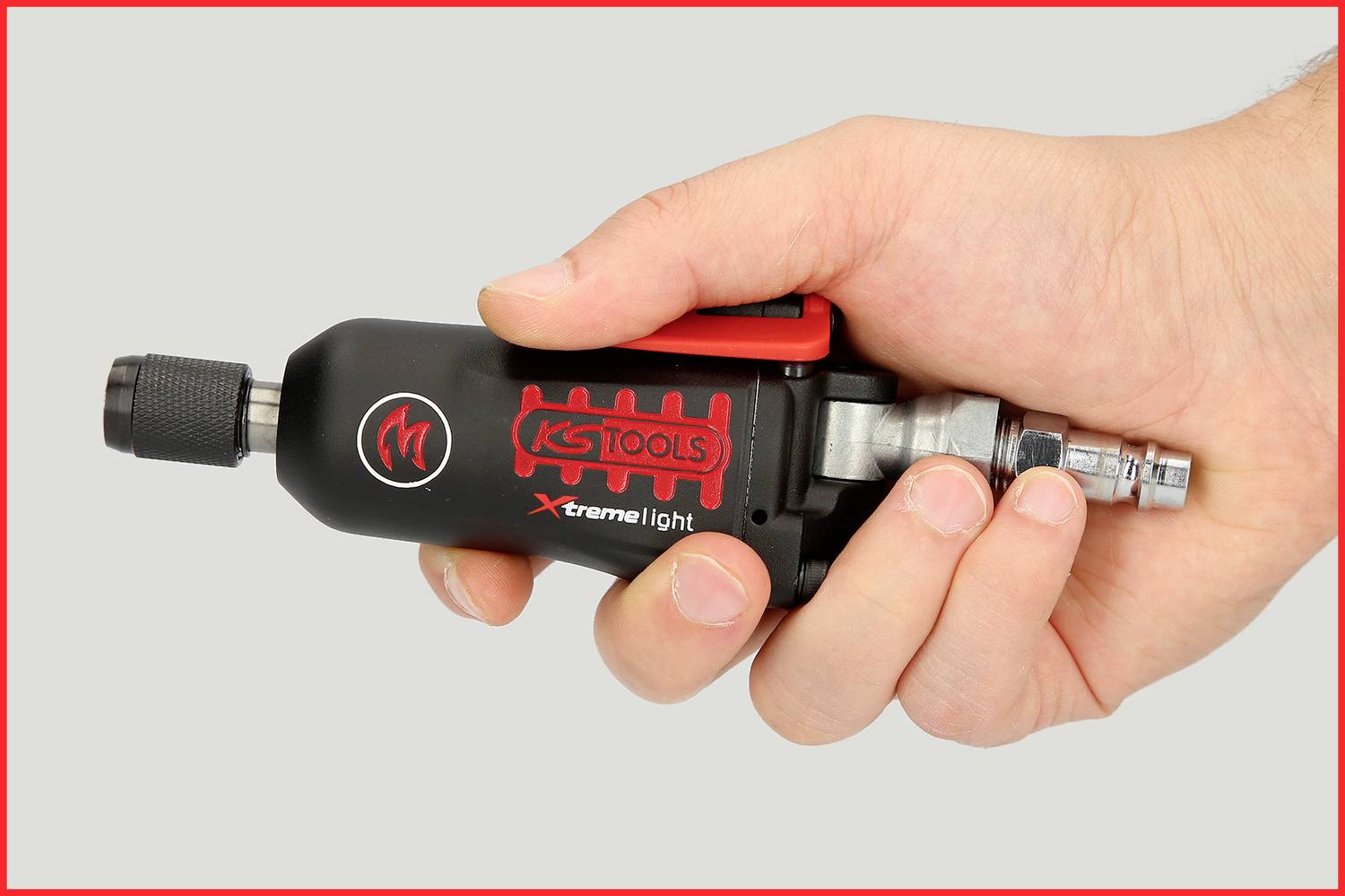 Eine Hand hält ein schwarzes Druckluftwerkzeug der Marke 'KS Tools Xtreme Light', bereit zur Benutzung, auf grauem Hintergrund.