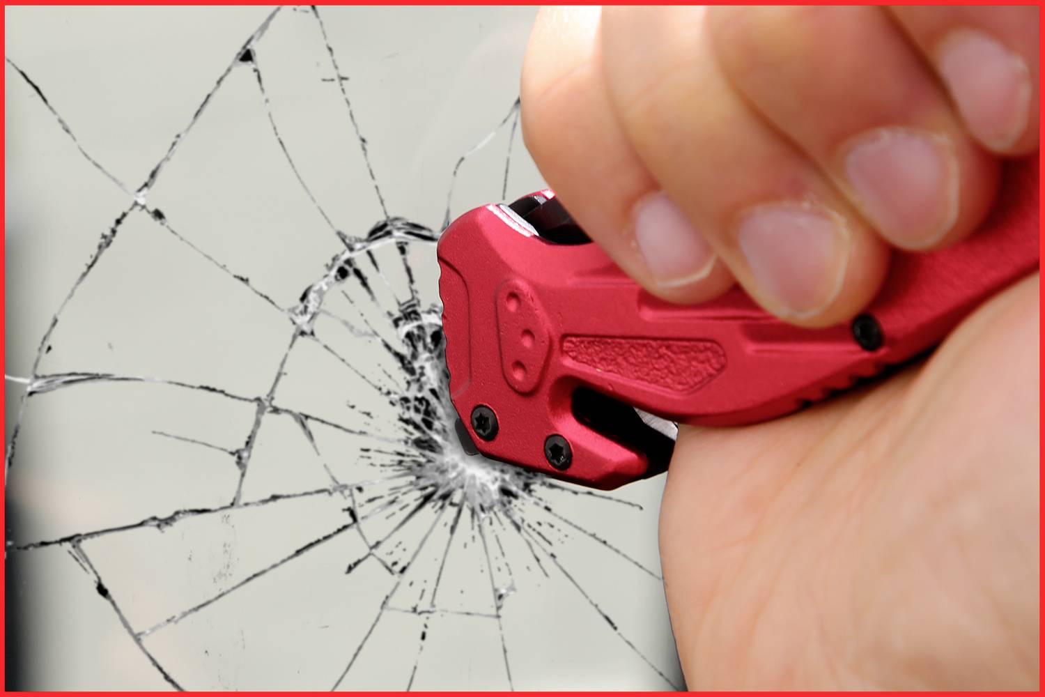 Eine Hand benutzt einen roten Notfallhammer, um eine Autoscheibe zu zerbrechen.