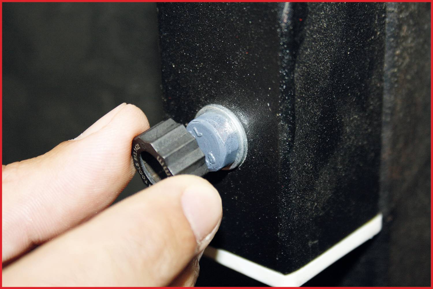 Eine Hand dreht einen schwarzen Drehknopf an einem Gerät mit schwarzer Oberfläche.