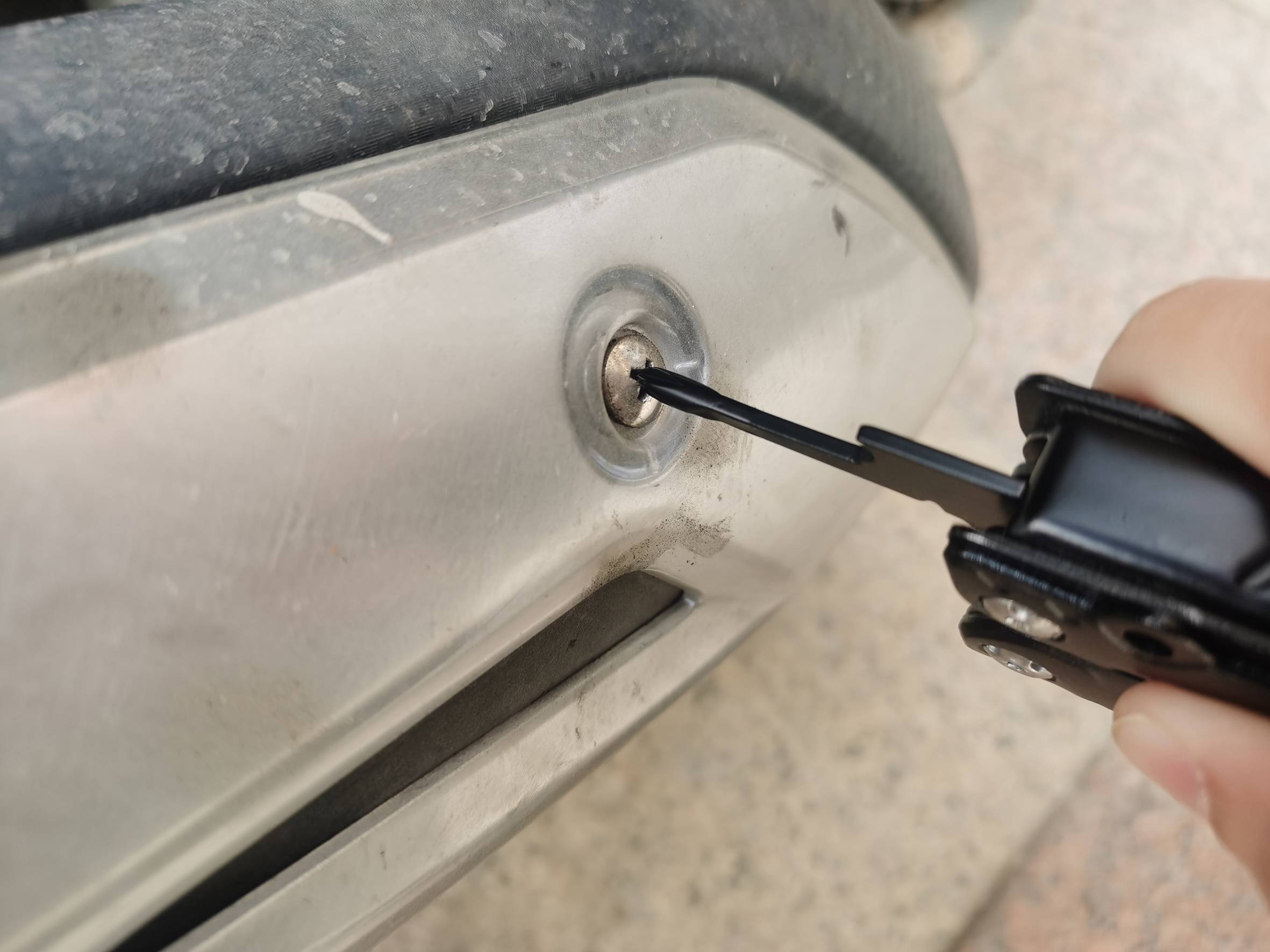 Eine Person verwendet ein Werkzeug, um eine Schraube an einem metallischen Gegenstand zu fixieren oder zu lösen.