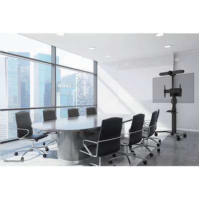 Konferenzraum mit großem Tisch und acht Stühlen, Blick auf moderne Hochhäuser durch große Fenster. Ein Bildschirm steht bereit.