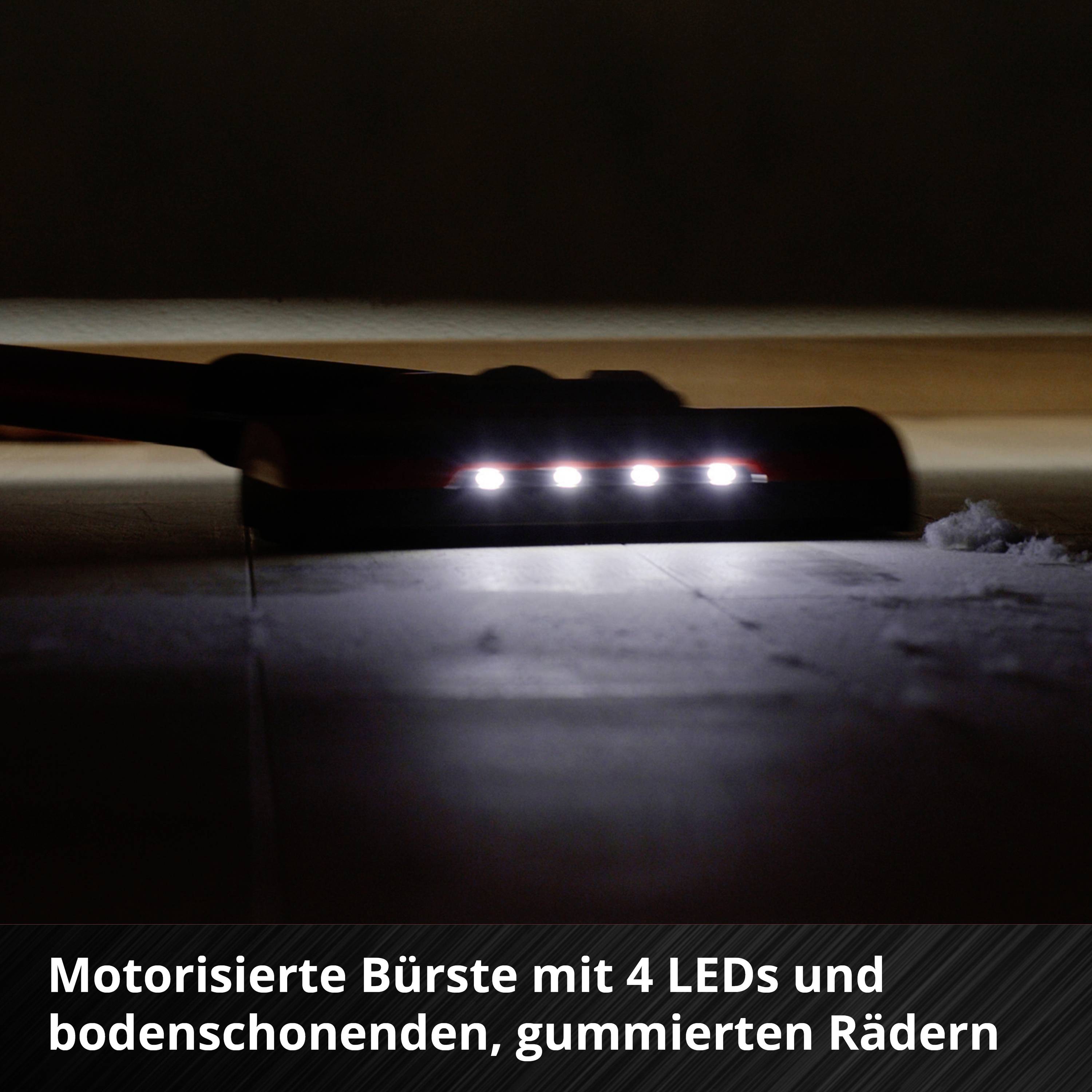 'Motorisierte Bürste mit 4 LEDs und bodenschonenden, gummierten Rädern.' Eine Staubsaugerdüse mit leuchtenden LED-Lichtern gegen einen dunklen Boden.