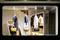 Schaufenster mit eleganter Kleidung: drei Outfits auf Puppen, je eins in Blau, Weiß mit Punkten und Gold, mit passenden Handtaschen.
