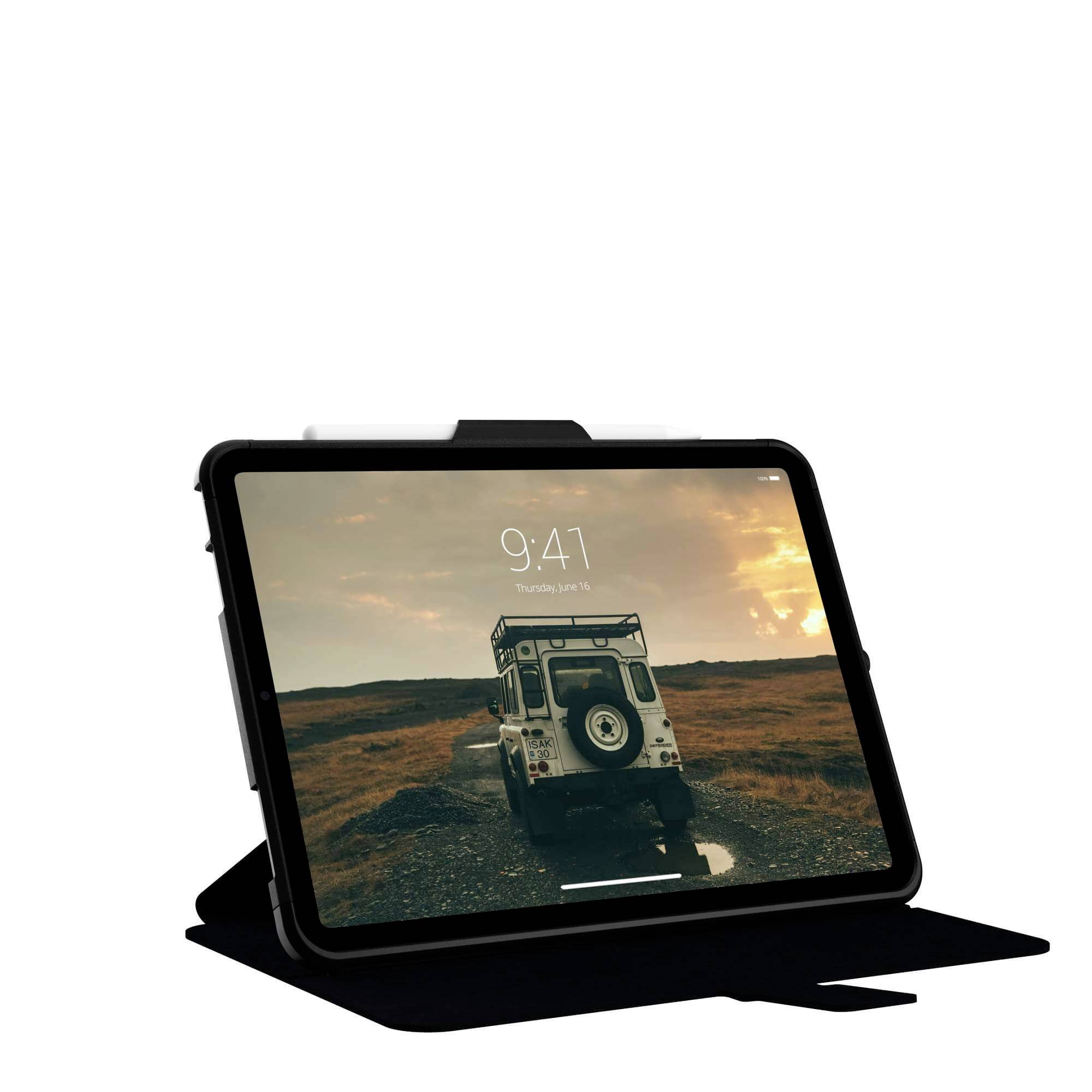 Ein Tablet zeigt ein Bild von einem Geländewagen auf einer unbefestigten Straße in einer ländlichen Landschaft bei Sonnenaufgang.