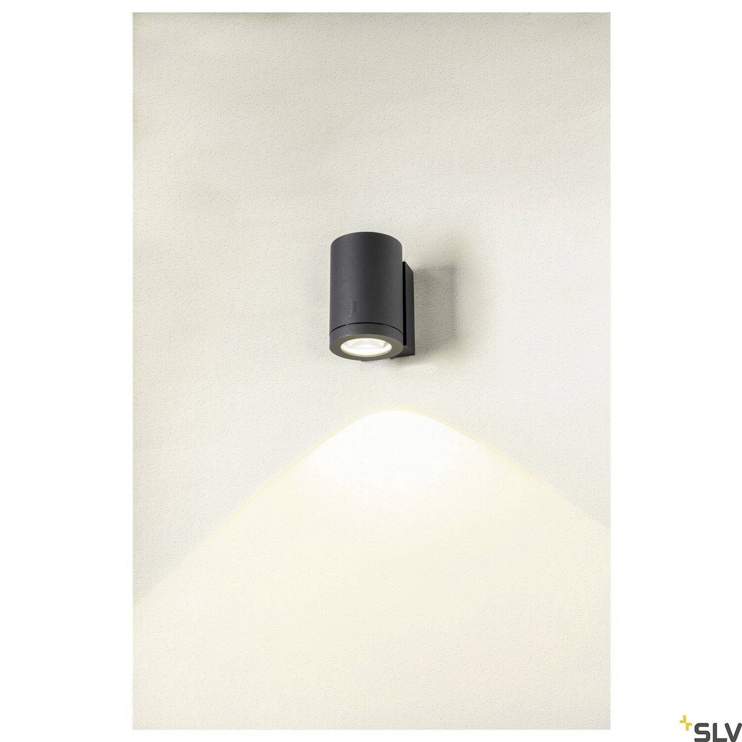 Wandleuchte mit zylindrischer Form, strahlt sanftes Licht nach oben und unten, montiert auf beige-grauer Wand.