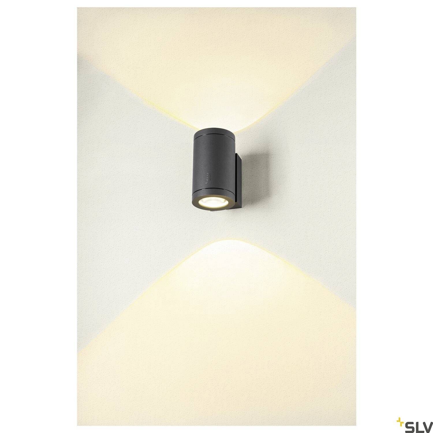 Eine wandmontierte Lampe strahlt Licht nach oben und unten aus, was dekorative Lichteffekte erzeugt und die Umgebung erhellt.