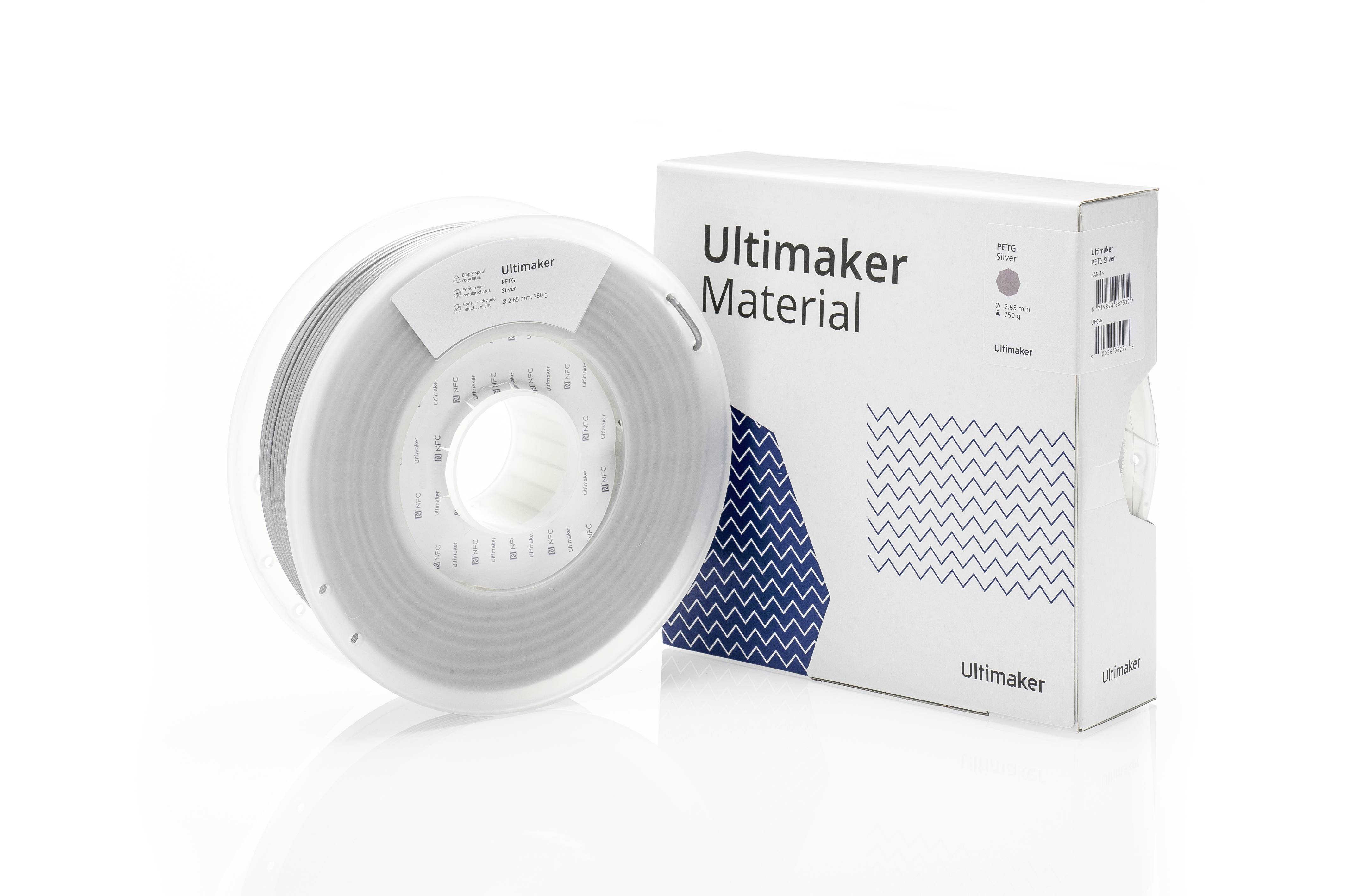 Eine Rolle graues Ultimaker 3D-Druckmaterial neben einer weißen Verpackung mit blauem Muster und dem Aufdruck 'Ultimaker Material'.