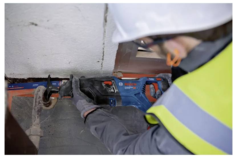 Ein Bauarbeiter mit Sicherheitsausrüstung verwendet eine Bosch-Reciprosäge, um an einer Baustelle ein Rohr zu durchtrennen.