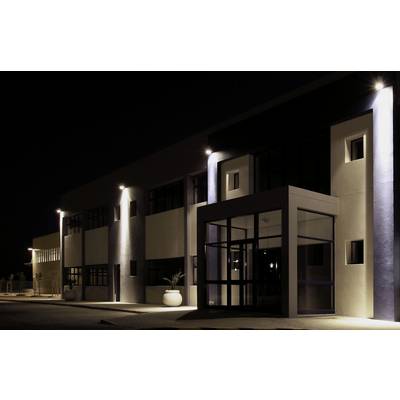 Ein modernes Gebäude bei Nacht, beleuchtet von mehreren Außenlampen. Dunkle Fenster und glatte Fassade betonen das architektonische Design.