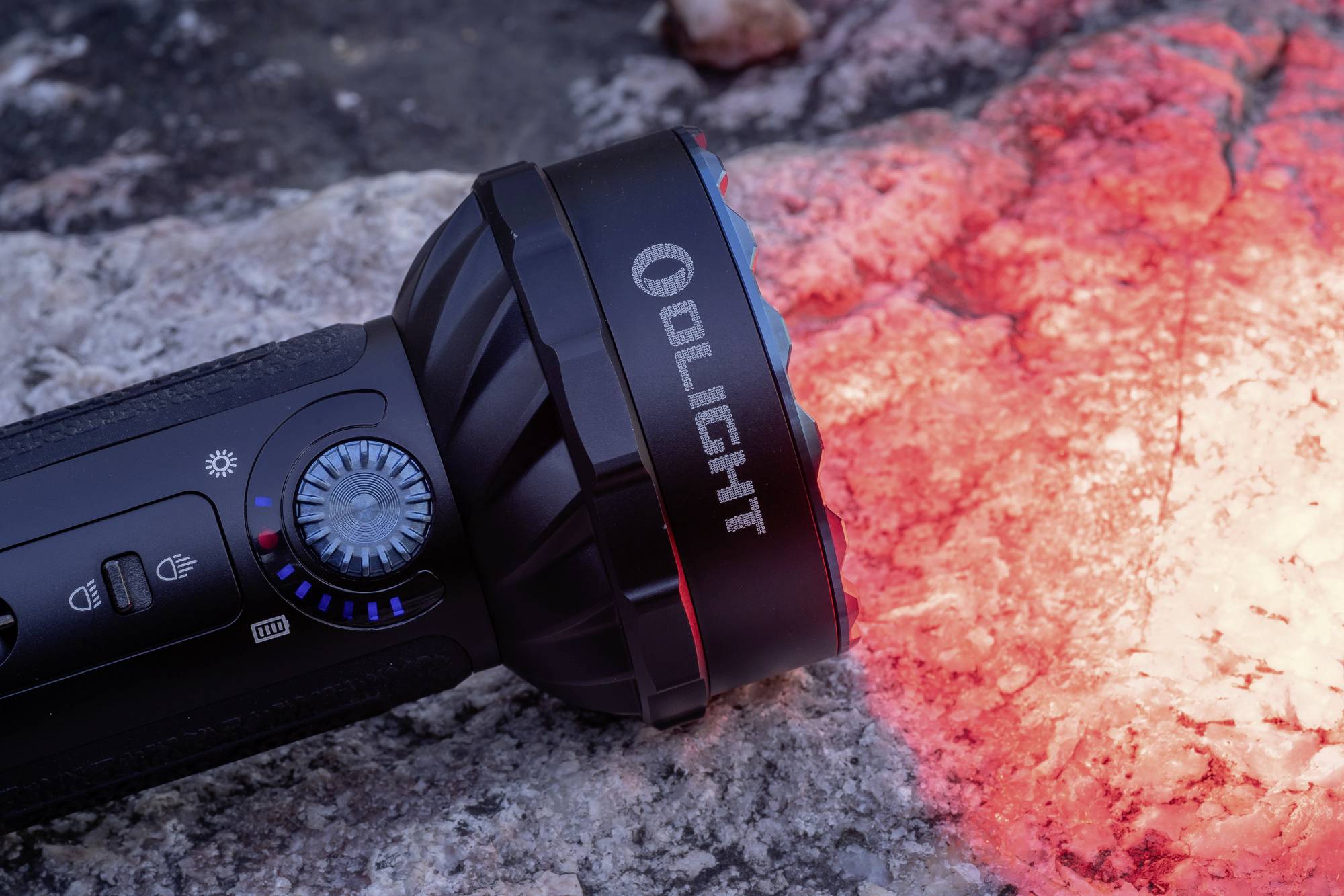 Eine schwarze Taschenlampe, die auf einem Felsen liegt und ihn mit rotem Licht beleuchtet.