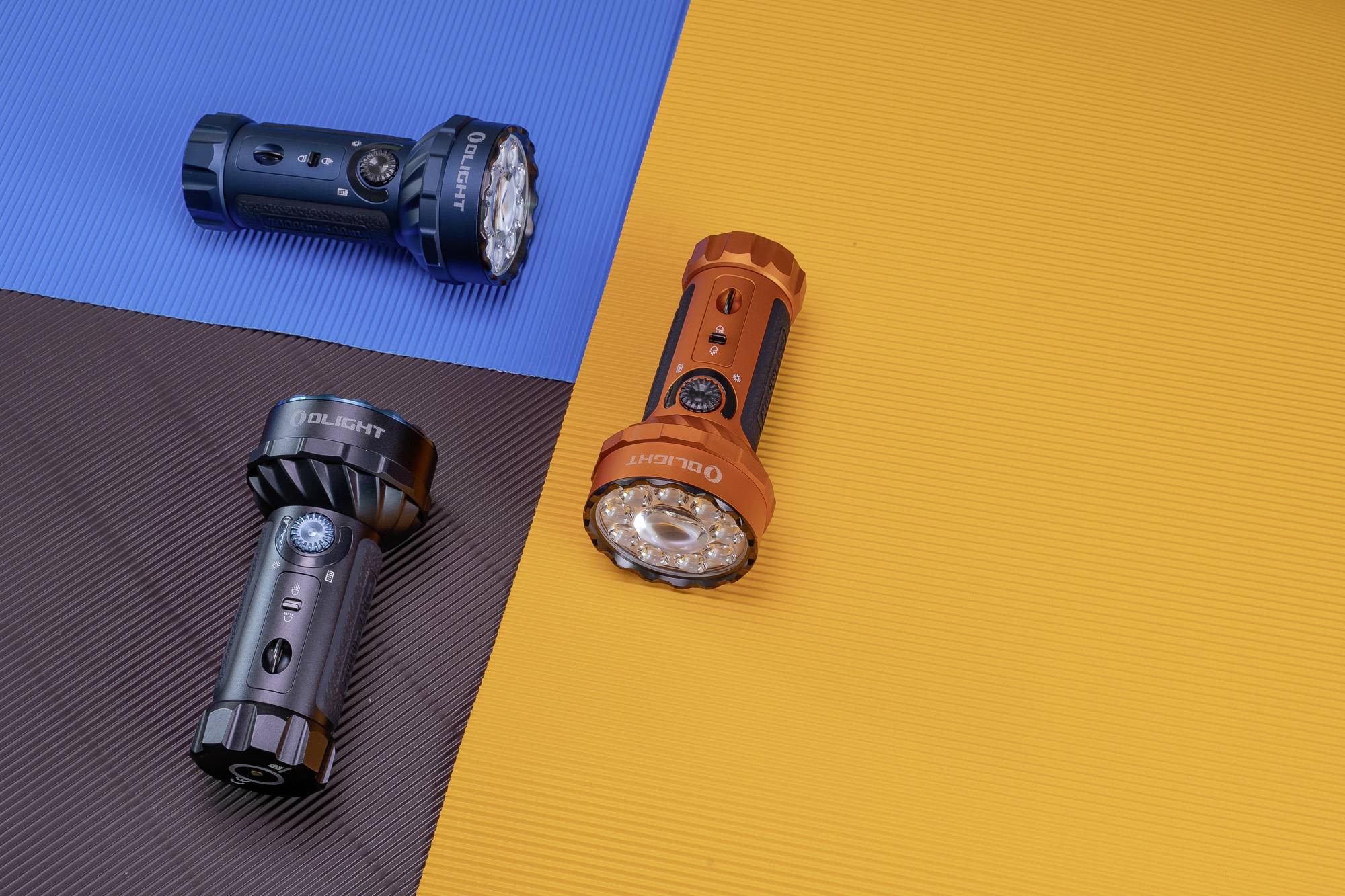 Drei Taschenlampen auf Hintergrund in Blau, Braun und Orange; eine blau, eine schwarz, eine orange. Die Lampen zeigen in verschiedene Richtungen.
