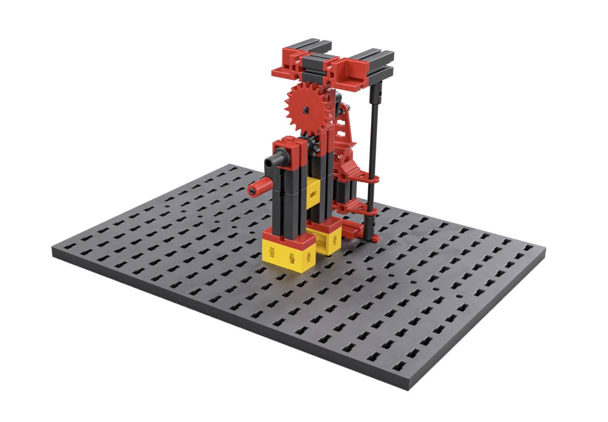 Baukasten-Modell einer mechanischen Vorrichtung auf grauer Lochplatte; rote Zahnräder und gelbe Bausteine; zeigt technische Konstruktion.