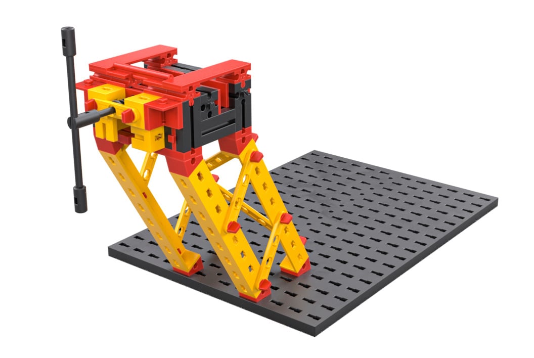 Ein Modell aus buntem Baukastensystem auf einer grauen Basisplatte, zeigt eine Hebevorrichtung mit Kurbelmechanismus.