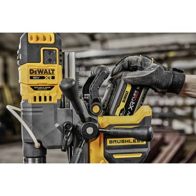 Eine Person ersetzt den Akku eines gelben, bürstenlosen DeWalt-Elektrowerkzeugs in einer Werkstattumgebung.