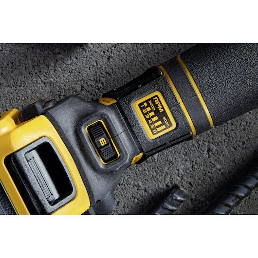 Nahaufnahme eines schwarz-gelben Werkzeuggriffs auf einer grauen Betonoberfläche, mit Leistungseinstellungsanzeige und Kontrollknopf.