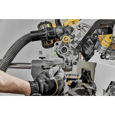 Nahaufnahme einer Person, die mit Handschuhen eine Gehrungssäge bedient. Die Säge schneidet ein Metallstück, Staubabsaugung angeschlossen.