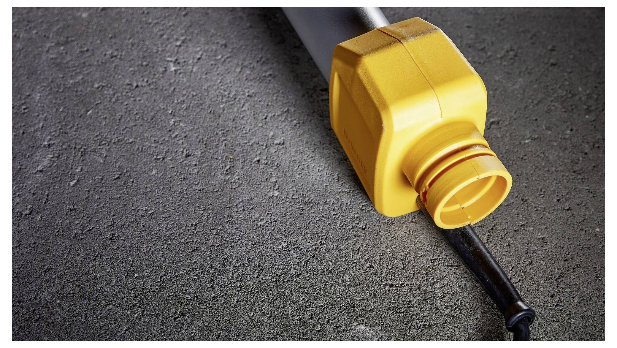 Gelber Plastikbehälter liegt geöffnet auf Betonboden, daneben liegt ein schwarzes Kabel.