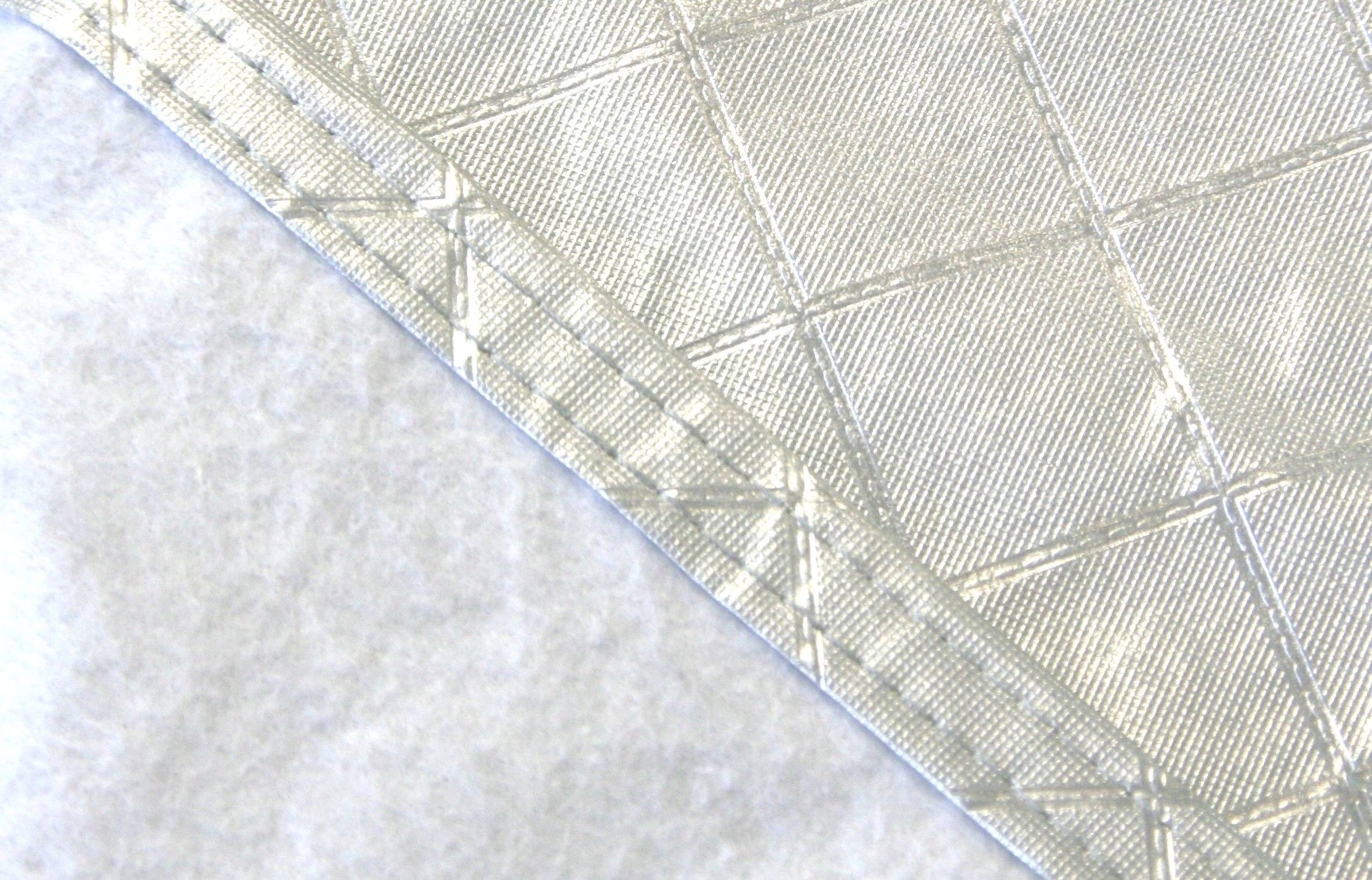 Nahaufnahme von zwei Stoffen mit unterschiedlichen Texturen und Mustern: eine glatte, gepolsterte Oberfläche und ein weiches, flauschiges Material.