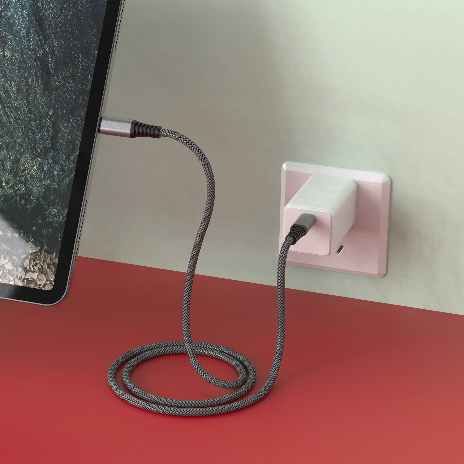 Ein Tablet wird über ein schwarzes Kabel, das an eine Steckdose angeschlossen ist, aufgeladen. Gerät zeigt eine Landschaft.