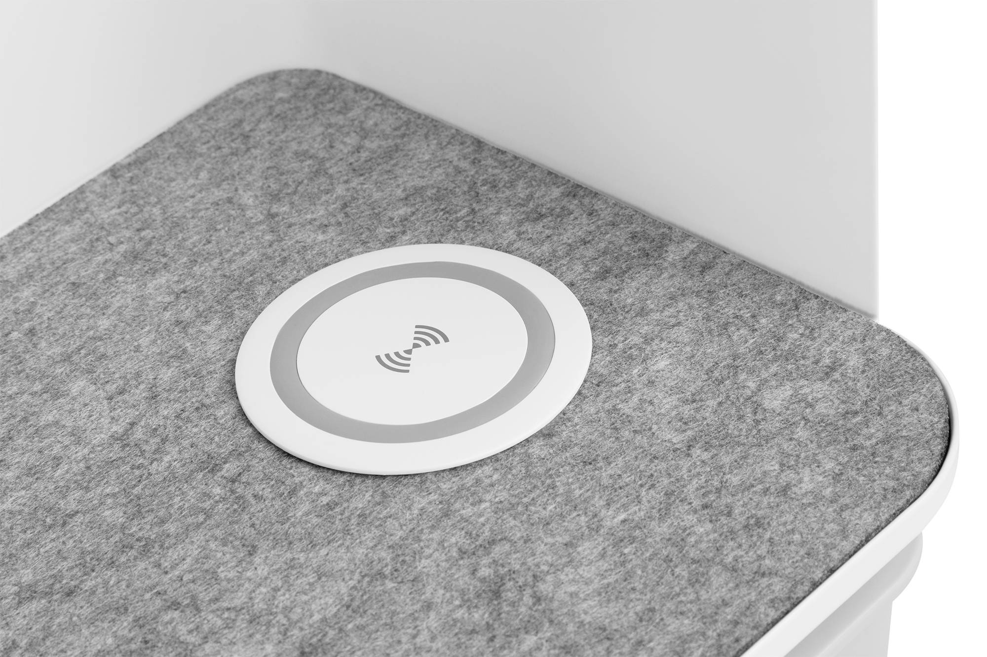 Eine graue Ablagefläche mit einem eingebauten kabellosen Ladepad in der Mitte. Das Ladepad zeigt ein Symbol für kabelloses Laden.