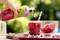 Eine Hand gießt ein rotes Getränk aus einer Flasche in ein mit Eiswürfeln gefülltes Glas. Im Hintergrund sind Himbeeren zu sehen.