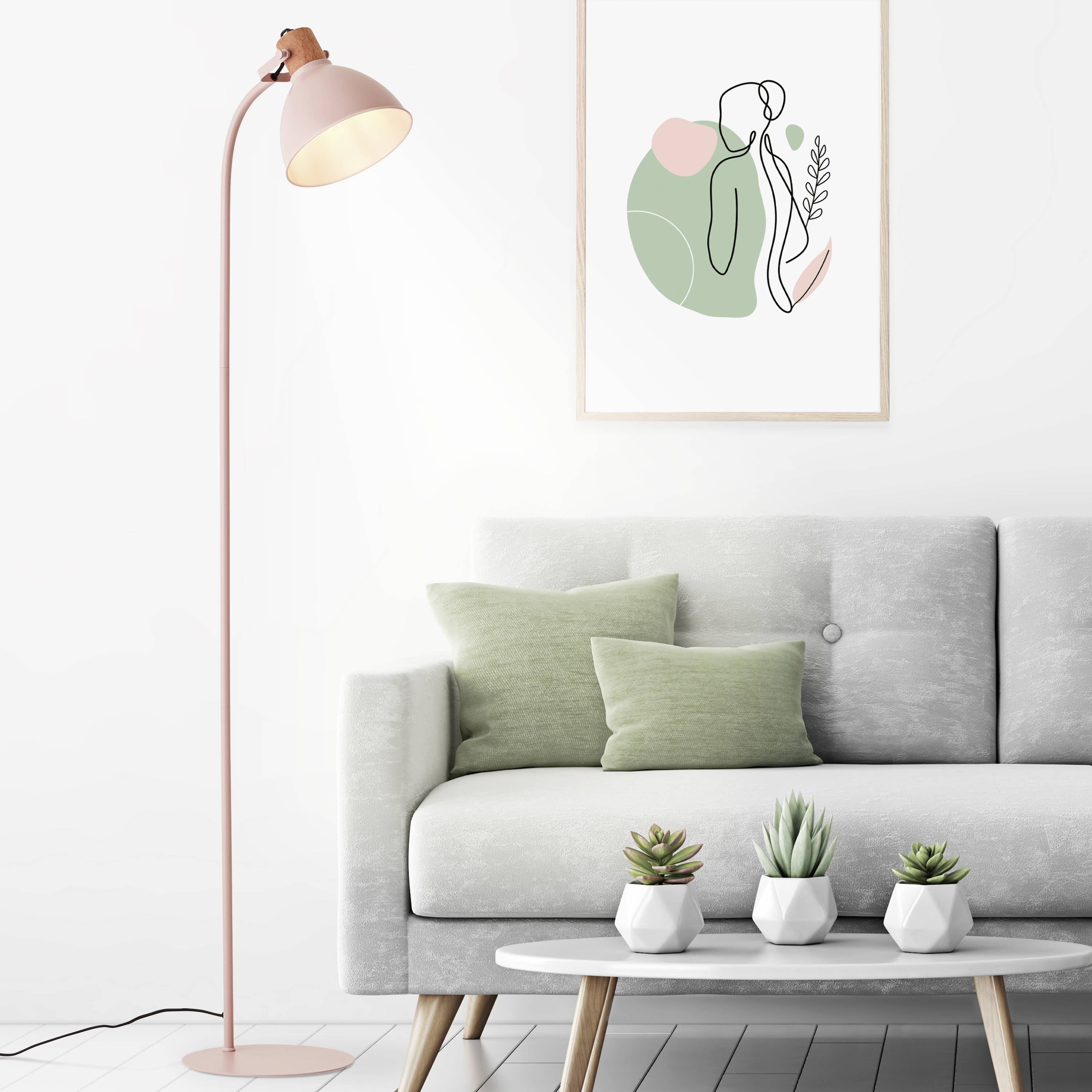 Ein helles Wohnzimmer mit einem blassrosa Stehlampe, einem grauen Sofa mit grünen Kissen und Kunstwerk mit abstrakten Formen an der Wand.