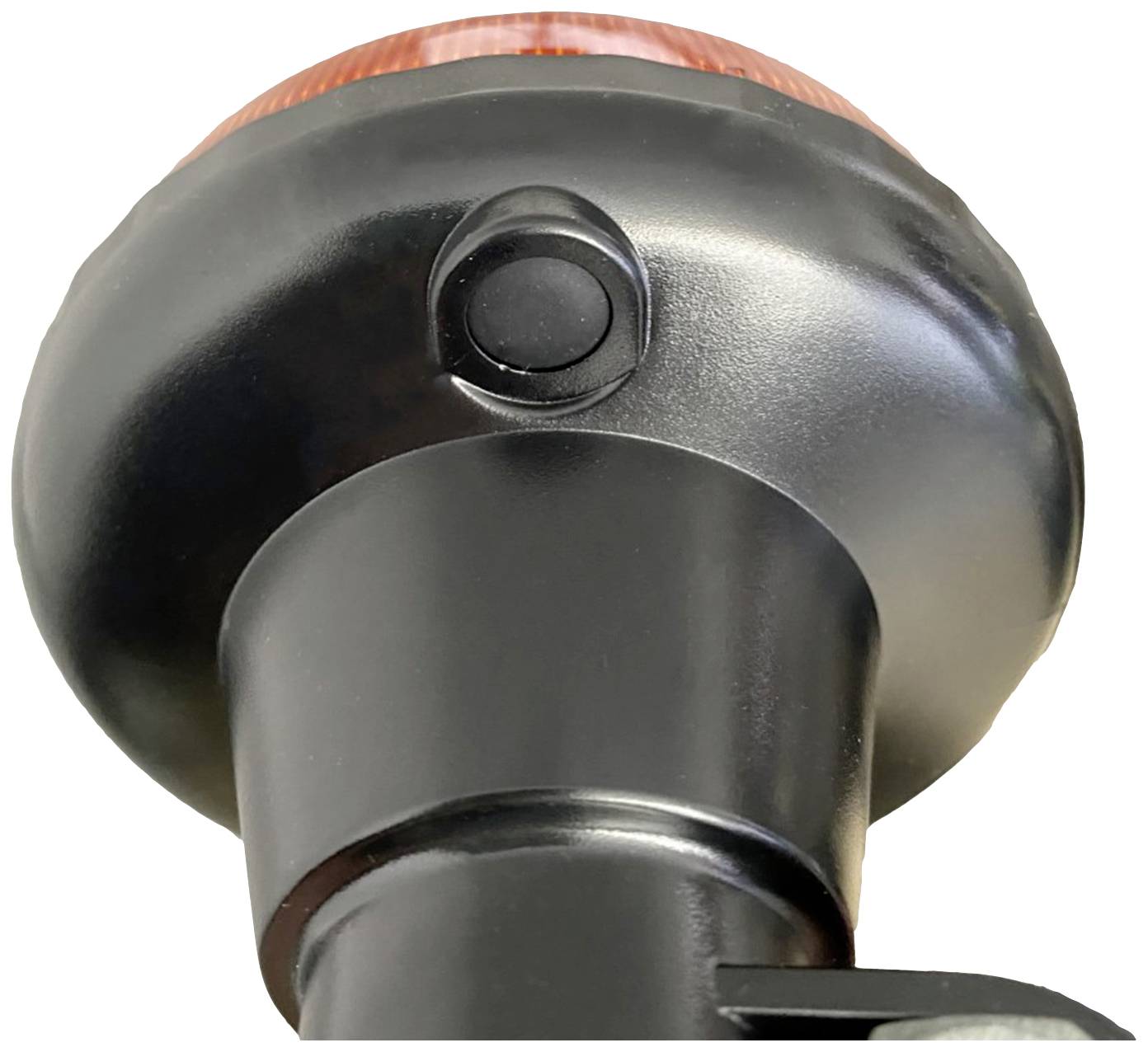 Nahaufnahme einer schwarzen, runden Lampe mit einem roten oberen Teil und einem zentralen Knopf.