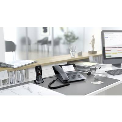 Ein aufgeräumter Büroschreibtisch mit Telefon, Notizen, Computer, und Dokumenten, beleuchtet von natürlichem Licht, im modernen Büro.