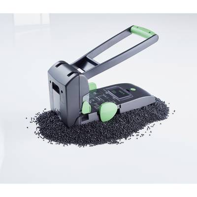 Ein schwarz-grüner Handstanzer steht auf einem Haufen kleiner schwarzer Granulate auf einer weißen Oberfläche.