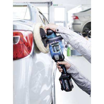 Eine Person poliert die glänzende Oberfläche eines Autos mit einer elektrischen Poliermaschine in einer Autowerkstatt.