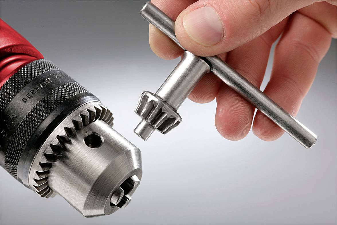 Eine Hand hält einen Schraubenschlüssel, um eine Bohrfutterschale zu drehen.