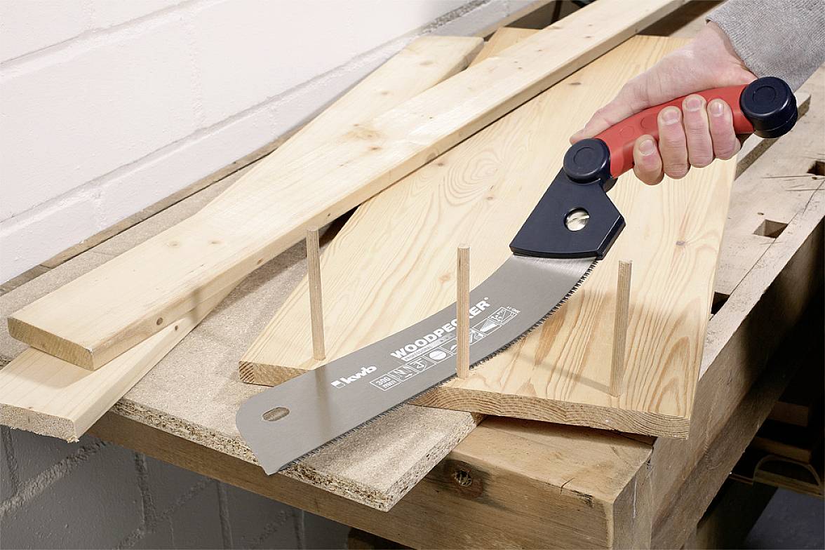 Eine Person sägt mit einer Japansäge mehrere Dübel bündig zur Holzoberfläche ab. Die Säge hat einen ergonomischen Handgriff.