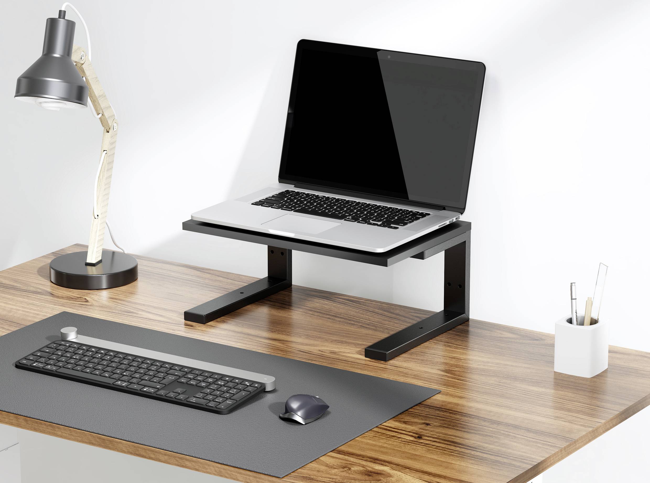 Ein Laptop auf einem höhenverstellbaren Ständer auf einem Schreibtisch, neben einer Lampe, Tastatur und Maus.