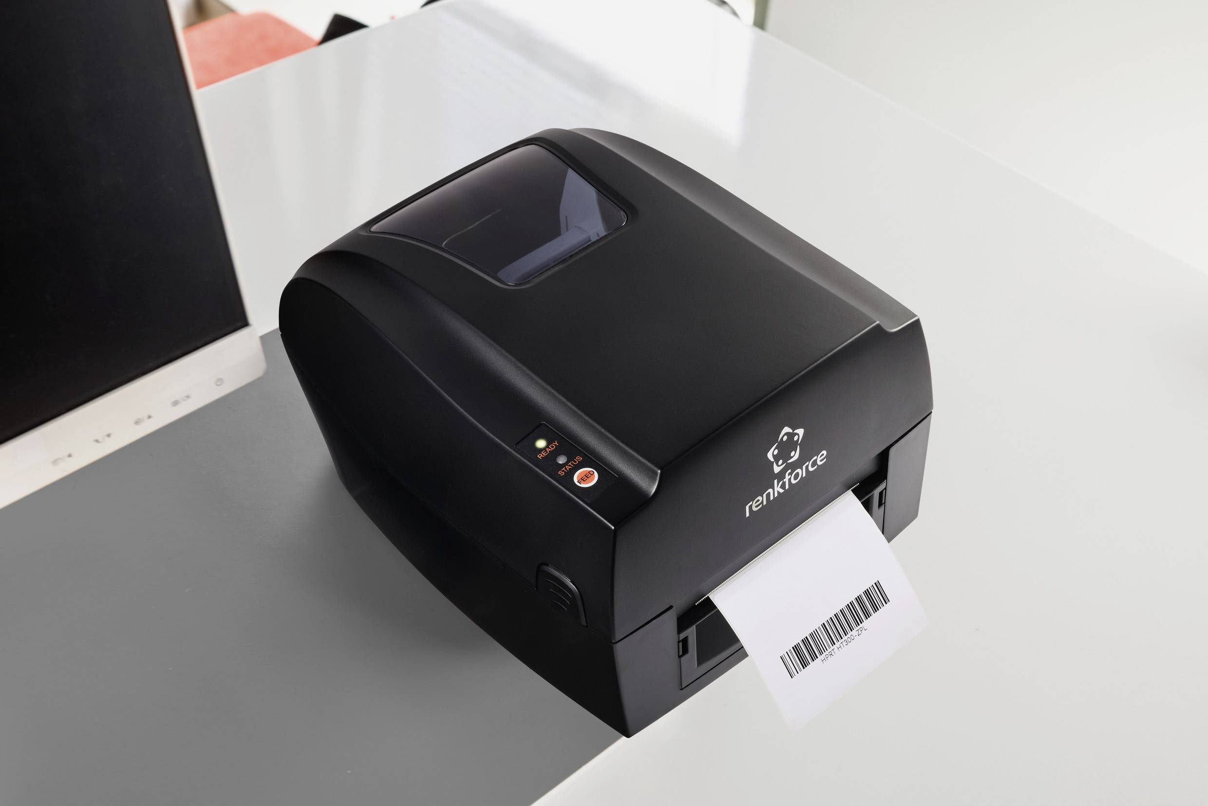 Ein schwarzer Drucker auf einem Tisch druckt ein Blatt mit einem Barcode.