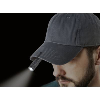 Ein Mann mit einem dunklen Basecap, an dem eine kleine Taschenlampe befestigt ist, die nach vorne leuchtet.