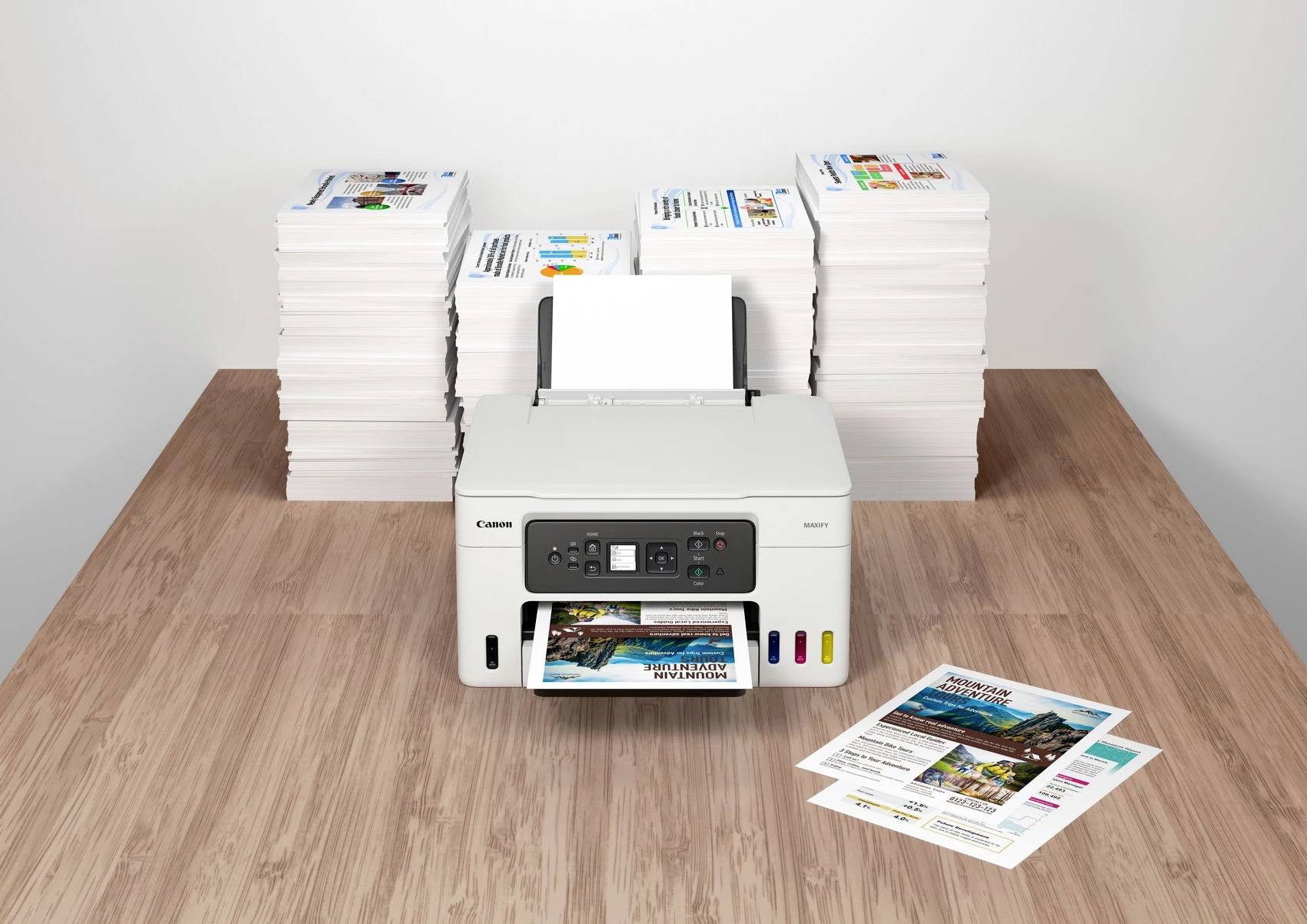 Ein Drucker auf einem Tisch druckt ein farbiges Foto. Im Hintergrund befinden sich stapelweise bedruckte Papiere.