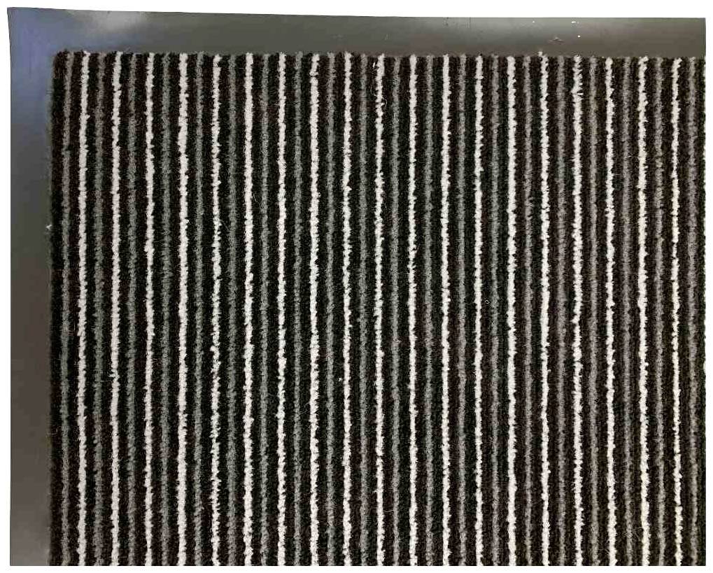Ein rechteckiger Teppich mit schwarz-weißen Längsstreifen liegt auf einem grauen Boden.