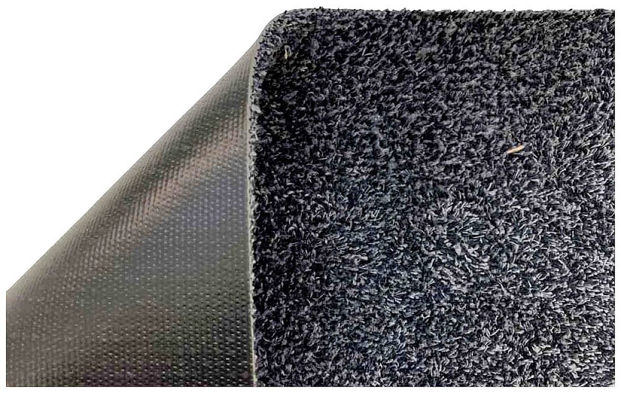 Schwarzer Bodenteppich, teilweise um eine Ecke gebogen, zeigt die Textur auf der Oberseite und die glatte Unterseite.
