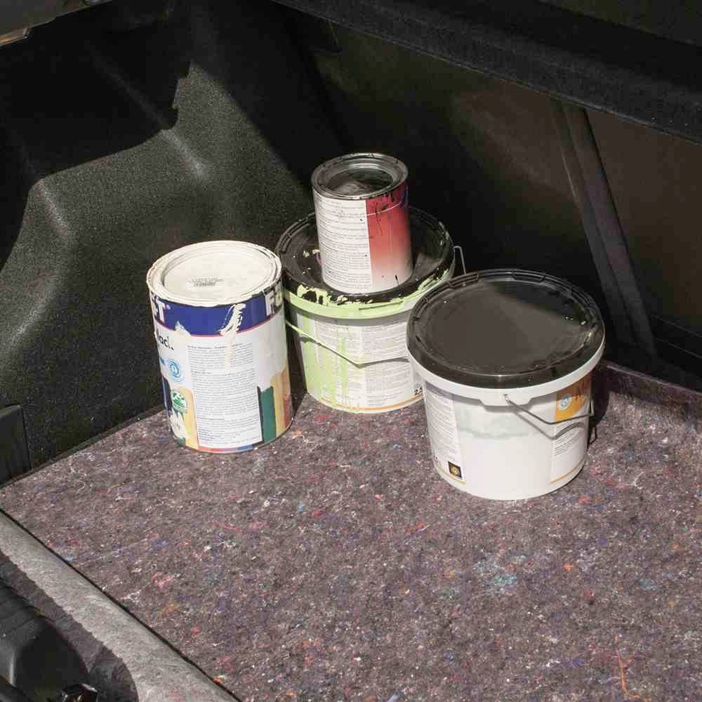 Vier Farbdosen stehen im Kofferraum eines Autos, auf einem dunklen Teppich liegend. Die Dosen sind teils geöffnet und farbverschmiert.