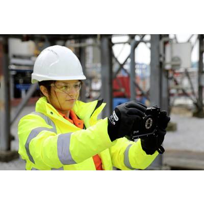 Eine Person in Schutzkleidung, einschließlich Helm und Brille, bedient ein technisches Gerät auf einer industriellen Baustelle.