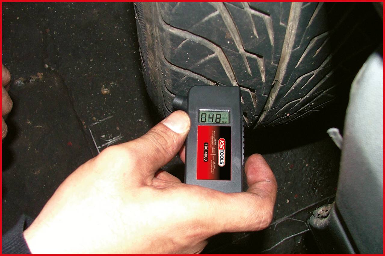 Eine Hand hält ein Messgerät, das die Profiltiefe eines Autoreifens von 4,8 mm anzeigt.