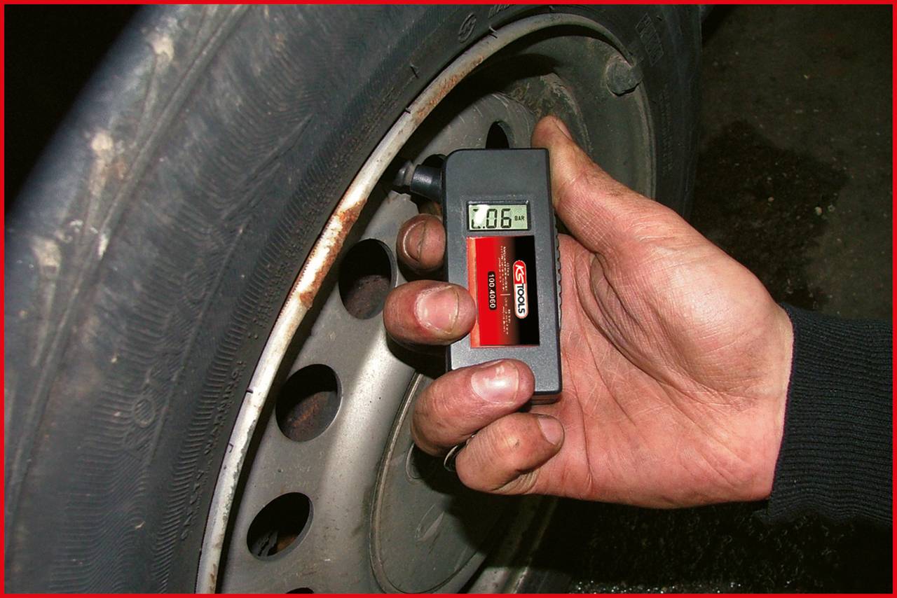 Eine Hand hält ein digitales Messgerät, das die Profiltiefe eines Autoreifens misst. Der Bildschirm zeigt '1.06' an.