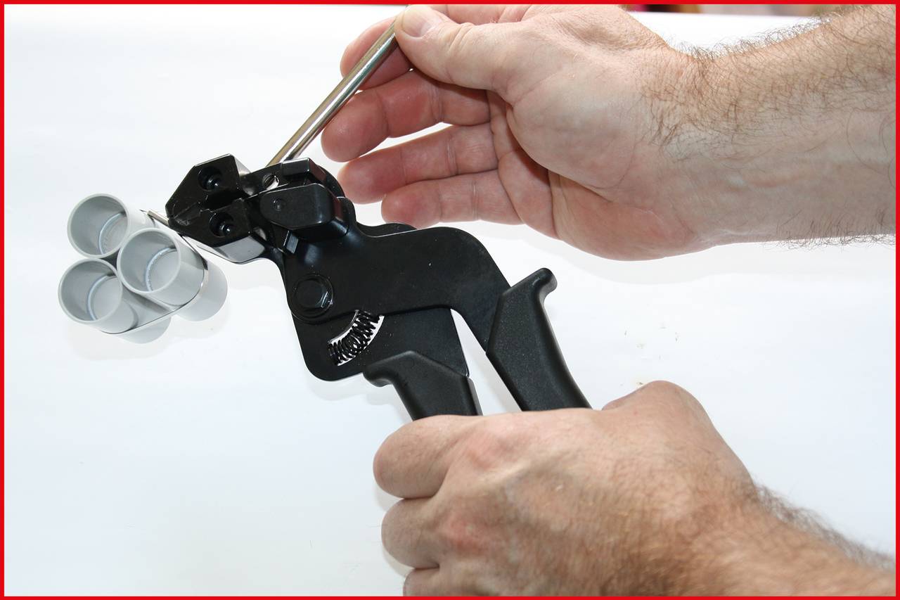 Eine Person repariert ein Werkzeug mit mehreren Metallteilen. Hände halten das Werkzeug und ein kleiner Stift wird eingesetzt.