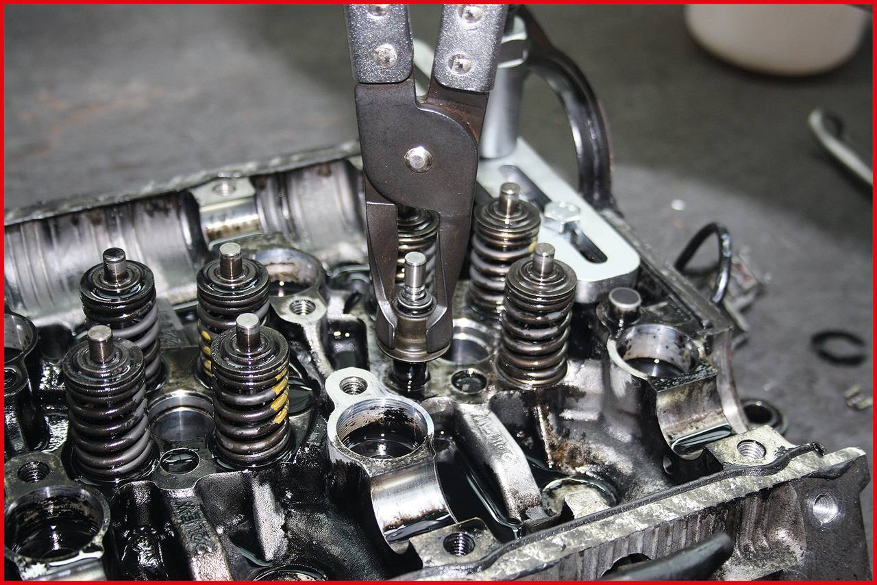 Motor mit geöffnetem Ventildeckel: Ein Werkzeug entfernt einen Ventileinsatz. Mechanischer Eingriff zur Reparatur oder Wartung.