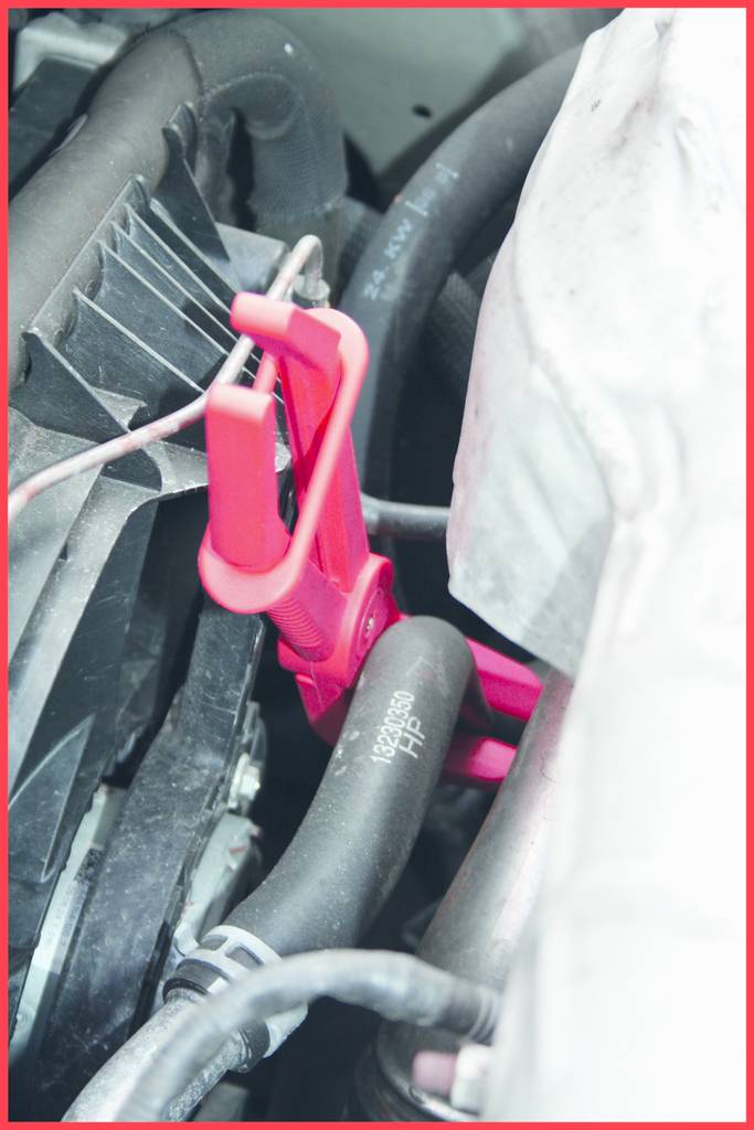 'Rosa Klammer' befestigt an einem schwarzen Rohr in einem Fahrzeugmotor.