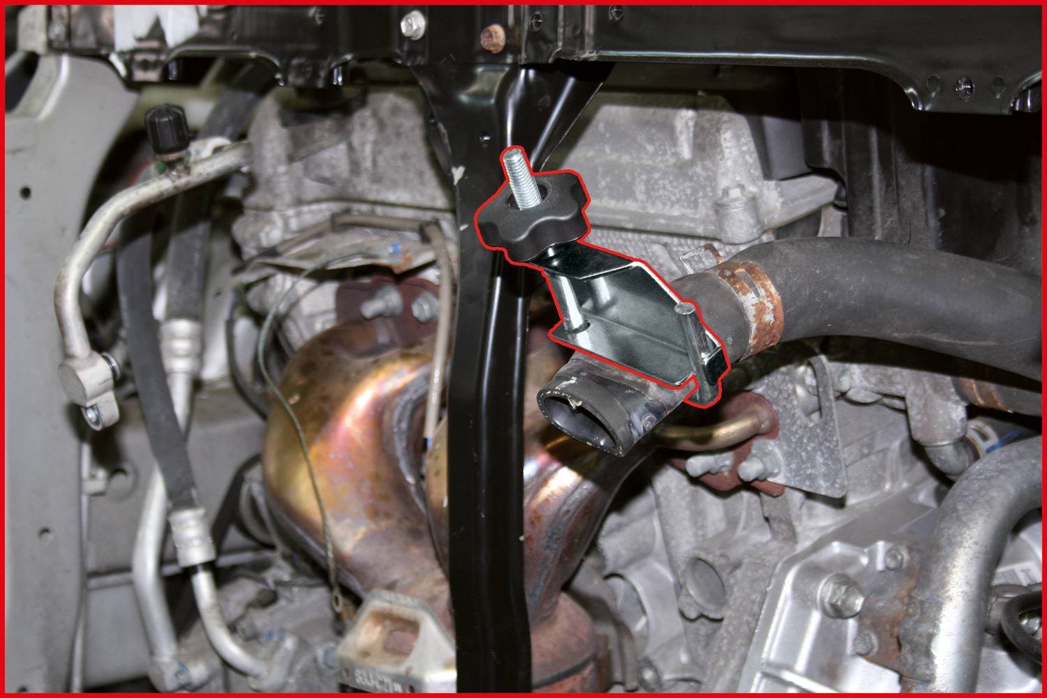 Detailaufnahme eines Automotors mit hervorgehobenem, rot umrandetem Teil an einem Rohr, das für technische Analyse oder Reparatur relevant ist.